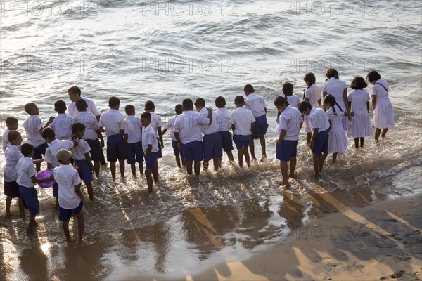 School children paddle in the sea on small sandy beach at Galle Face Green, Colombo, Sri Lanka, Asia