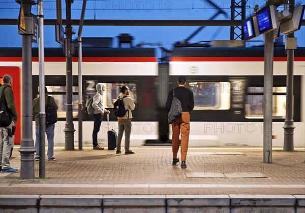 People on the platform early in the morning with passing train, Central Station, Witten, North Rhine-Westphalia, Germany, Europe