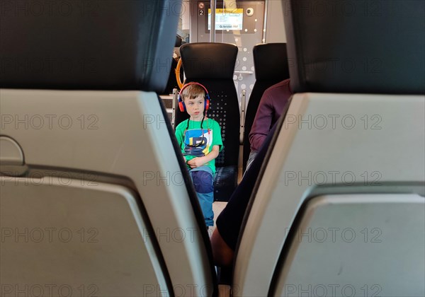 View of a young boy with headphones on a local train travelling through East Westphalia, Germany, Europe