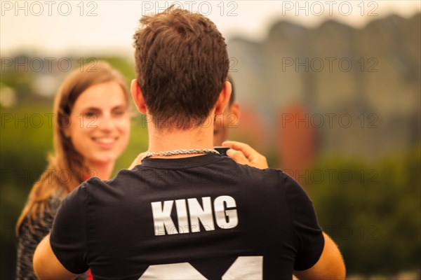 Back view of a couple, with a man wearing a T-shirt with the inscription 'KING', Hohenzollernbruecke, Cologne Deutz, North Rhine-Westphalia, Germany, Europe