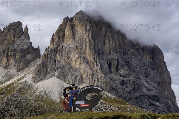 Traditional traditional costume couple advertising sign on the Sella Pass, behind Sassolungo, South Tyrol, Italy, Europe