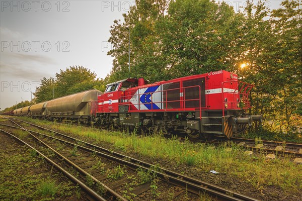 Locomotive pulling freight wagon on tracks at dusk, Lower Rhine, North Rhine-Westphalia, Germany, Europe