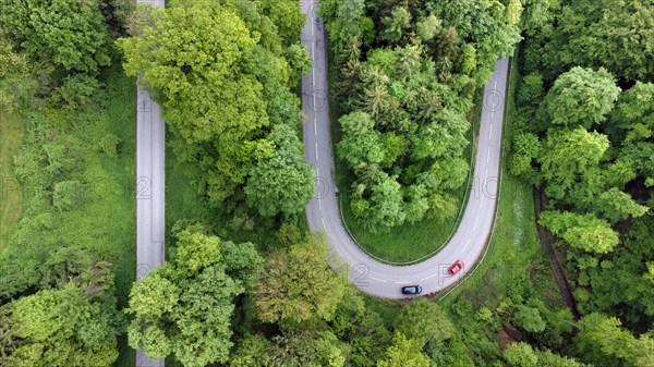A red and a black car driving on a serpentine road through a green landscape, drone shot, Upper Bavaria, Bavaria, Germany, Europe