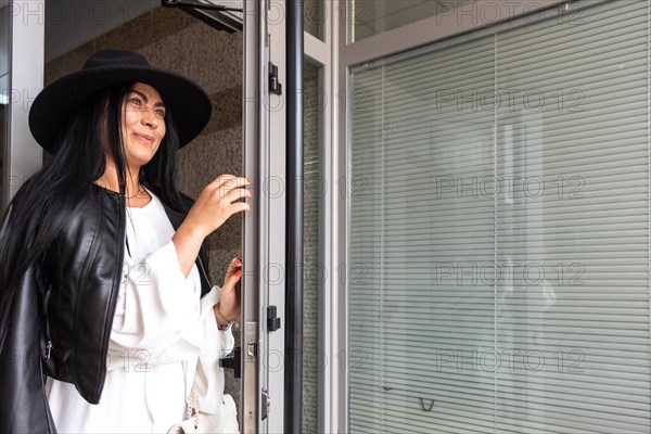 Woman in a black hat coming out of her apartment