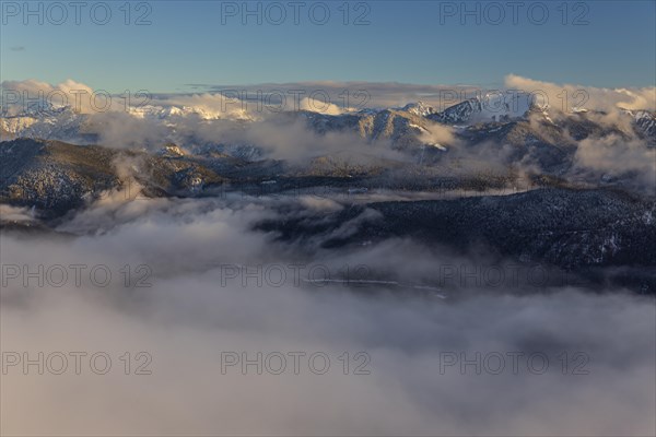 Distant view over mountain lake in the evening light, snow-covered mountains, clouds and fog, winter, view from Herzogstand to Walchensee, Bavarian Alps, Upper Bavaria, Bavaria, Germany, Europe