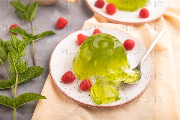 Mint and raspberry green jelly on gray concrete background and orange linen textile. side view, close up, selective focus