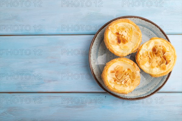 Traditional portuguese cakes pasteis de nata, custard small pies with almonds on blue wooden background. Top view, flat lay, copy space