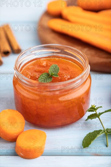 Carrot jam with cinnamon in glass jar on blue wooden background. Side view, close up, selective focus