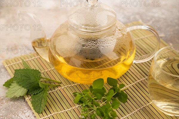 Green oolong tea with herbs in glass on brown concrete background. Healthy drink concept. Side view, close up, selective focus