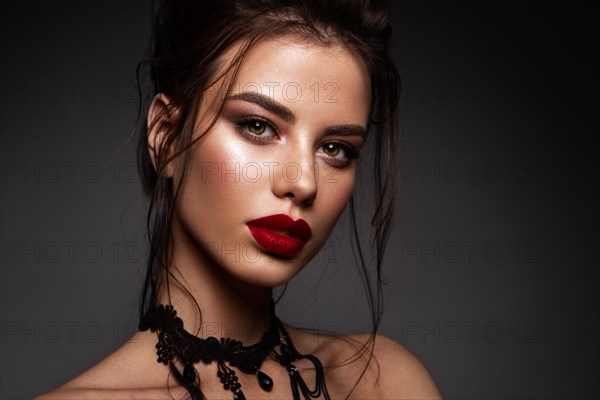 Gorgeous Young Brunette Woman face portrait. Beauty Model Girl with bright eyebrows, perfect make-up, red lips, touching her face. Sexy lady makeup for party