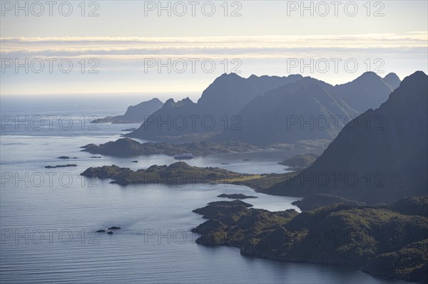 View of the coast in Ulvagsundet fjord and mountains in the evening light, Hurtigruten cruise ship in the fjord, view from the summit of Dronningsvarden or Stortinden, Vesteralen, Norway, Europe