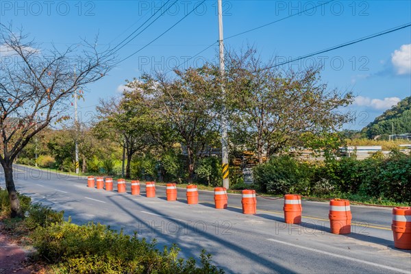 Orange traffic barrels next to double yellow line on paved road