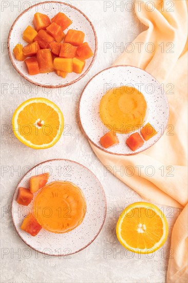 Papaya and orange jelly on gray concrete background and orange linen textile. top view, flat lay, close up