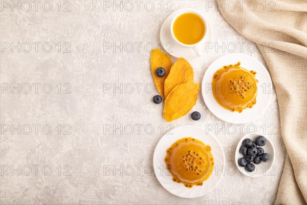 Mango and passion fruit jelly with blueberry on gray concrete background and linen textile. top view, flat lay, copy space