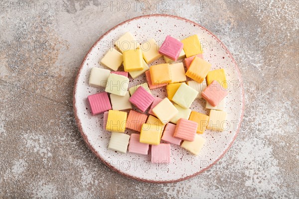 Various fruit jelly chewing candies on plate on brown concrete background. apple, banana, tangerine, top view, flat lay, close up