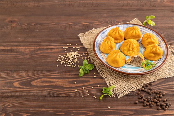 Fried manti dumplings with pepper, basil on brown wooden background and linen textile. Side view, copy space