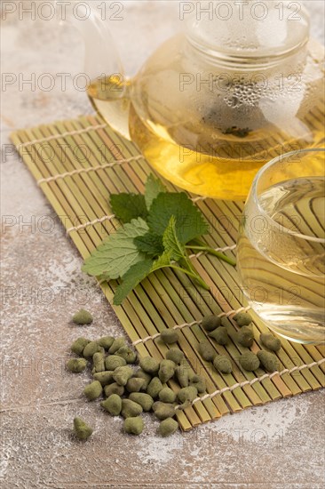 Green oolong tea with herbs in glass on brown concrete background. Healthy drink concept. Side view, close up