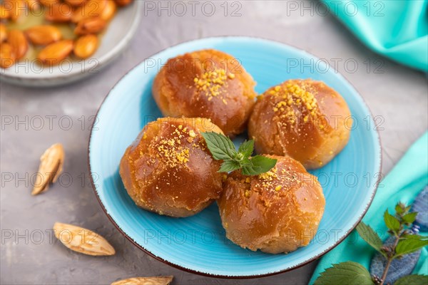 Homemade traditional turkish dessert sekerpare with almonds and honey, cup of green tea on gray concrete background and blue textile. side view, selective focus