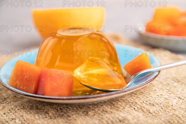 Papaya and orange jelly on gray concrete background and linen textile. side view, close up, selective focus
