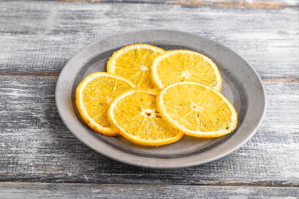 Orange chips on a gray plate on a gray wooden background. Side view, close up