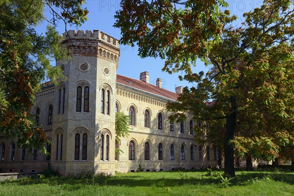 A historic Gothic-style castle surrounded by autumn trees under a clear blue sky, Officers' Palace, Komarno, Komarom, Komorn, Nitriansky kraj, Slovakia, Europe