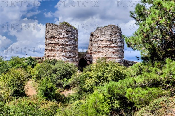 Remains of brick and stone castle towers on hillside under cloudy sky in Istanbul, Tuerkiye