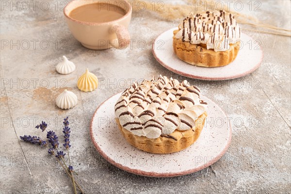 Two tartlets with meringue cream and cup of coffee on brown concrete background. side view. Breakfast, morning, concept