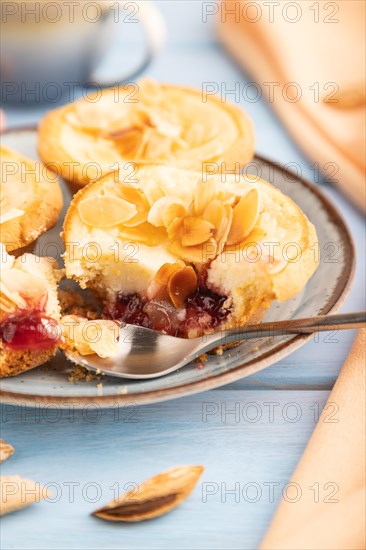 Traditional portuguese cakes pasteis de nata, custard small pies with almonds with cup of coffee on blue wooden background and orange textile. Side view, close up, selective focus