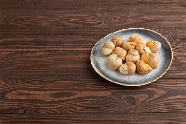 Grape (Burgundy) snails with butter and cheese on brown wooden background. Side view, copy space