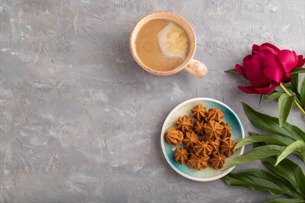 Homemade soft caramel fudge candies on blue plate and cup of coffee on gray concrete background, peony flower decoration. top view, flat lay, copy space