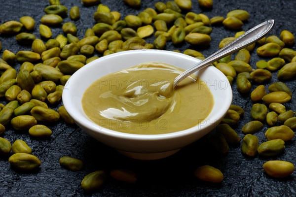 Pistachio cream in small bowls with spoon, pistachios