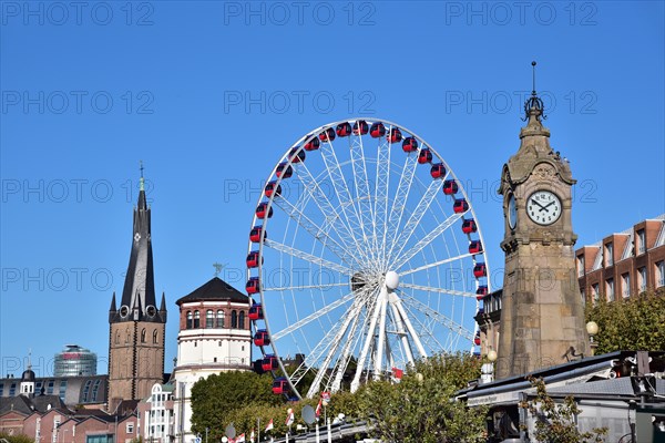 View over the Rhine terrace of Duesseldorf with the church tower of Sankt Lambertus, the castle tower, the Ferris wheel of the funfair and the water gauge for the Rhine level, North Rhine-Westphalia, Germany, Europe