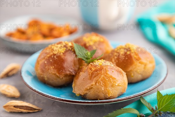 Homemade traditional turkish dessert sekerpare with almonds and honey, cup of green tea on gray concrete background and blue textile. side view, selective focus