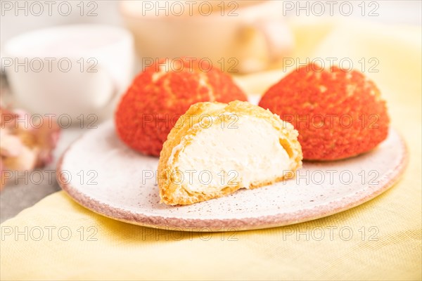 Traditional french custard dessert shu cake and cup of green tea on brown concrete background and yellow linen textile. side view, selective focus. Breakfast, morning, concept