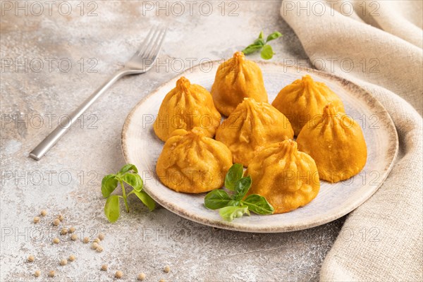 Fried manti dumplings with pepper, basil on gray concrete background and linen textile. Side view, close up