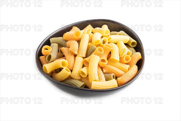 Rigatoni colored raw pasta in bowl isolated on white background. Side view