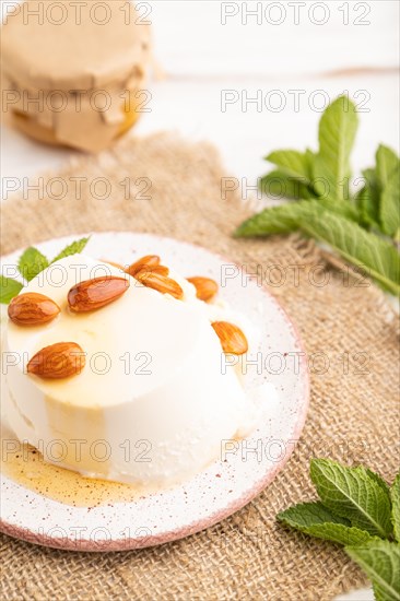 Ricotta cheese with honey and almonds on white wooden background and linen textile. side view, close up, selective focus