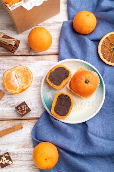 Truffle chocolate tangerine candies on a white wooden background and blue linen textile. top view, flat lay, close up