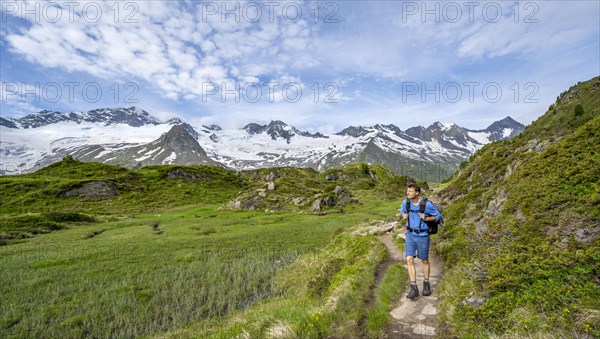 Mountaineer on hiking trail in picturesque mountain landscape, mountain peaks with snow and glacier Hornkees and Waxeggkees, summit Grosser Moeseler and Hornspitzen, Berliner Hoehenweg, Zillertal Alps, Tyrol, Austria, Europe
