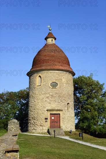 A historic stone tower with a reddish tiled roof under a clear blue sky surrounded by green grass, Rotunda of St.Juraj, Skalica, Skalica, Trnavsky kraj, Slovakia, Europe