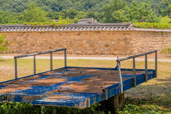 Rural setting of blue trailer in shade with oriental wall in background