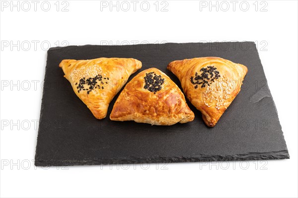 Homemade asian pastry samosa on black slate board isolated on white background. side view, close up