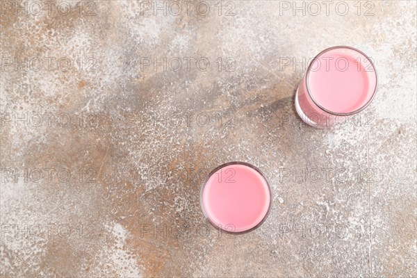 Sweet strawberry liqueur in glass on a gray concrete background. top view, copy space, flat lay