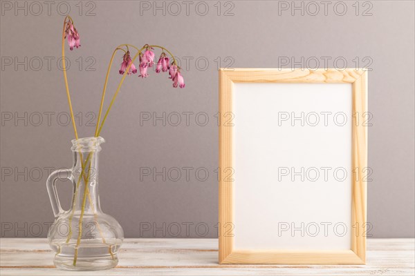 Wooden frame with pink dicentra, broken heart in glass on gray pastel background. side view, copy space, mockup, template, spring, summer minimalism concept
