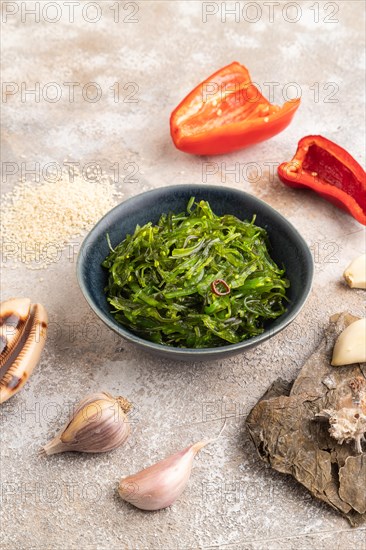 Chuka seaweed salad in blue ceramic bowl on brown concrete background. Side view, close up