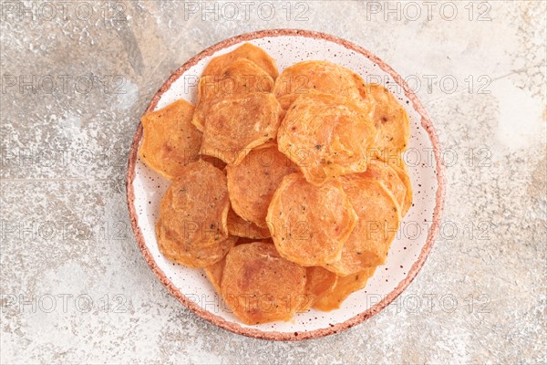 Slices of dehydrated salted meat chips with herbs and spices on gray concrete background. Top view, flat lay, close up