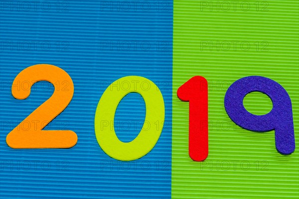 The numbers 2019 made of felt of different colors photographed on blue and green corrugated background