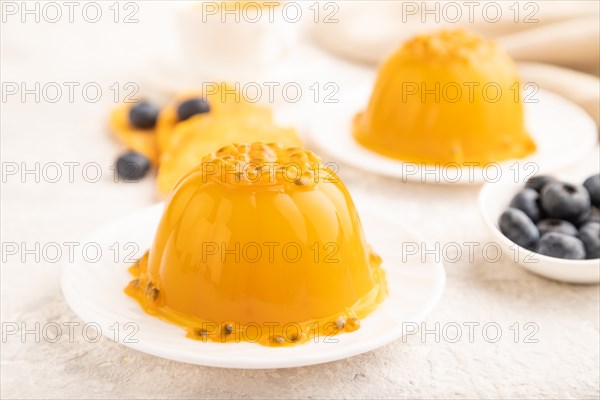 Mango and passion fruit jelly with blueberry on gray concrete background and linen textile. side view, close up, selective focus