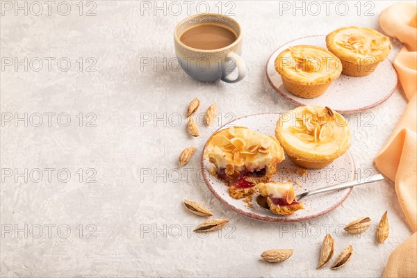 Traditional portuguese cakes pasteis de nata, custard small pies with almonds with cup of coffee on gray concrete background and orange textile. Side view, copy space