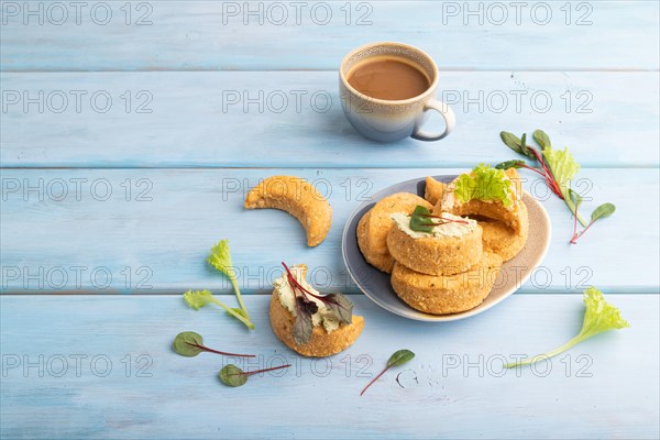 Homemade salted crescent-shaped cheese cookies, cup of coffee on blue wooden background. side view, copy space